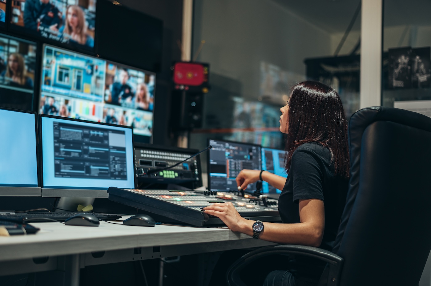 A media operator working at a bank of monitors in a broadcast control room