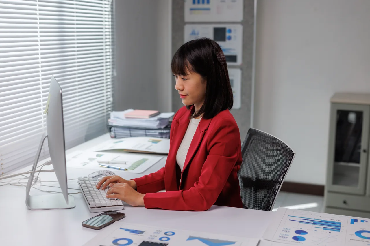 An accountant working at a desktop computer in an office