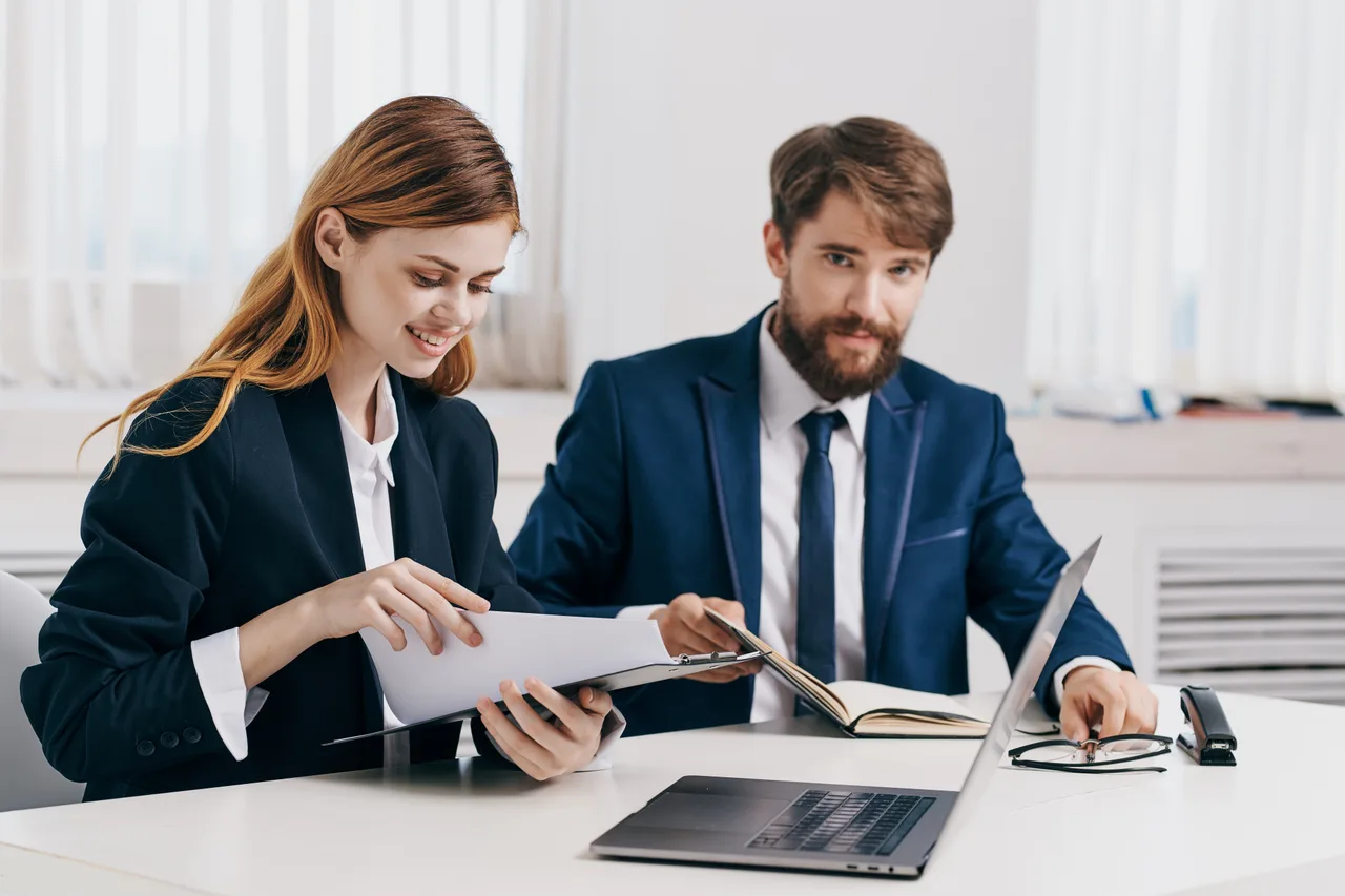 Two finance colleagues reviewing documents at a shared desk