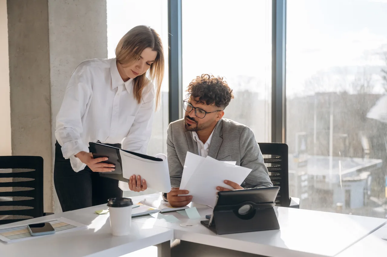Two accountants reviewing documents together in a bright office