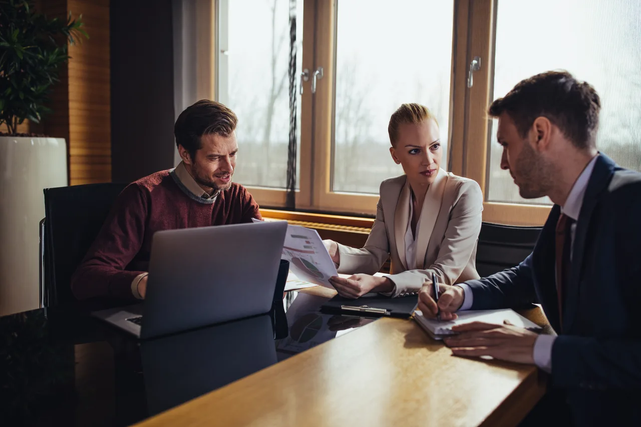 Colleagues working through a plan together on a laptop in a meeting room