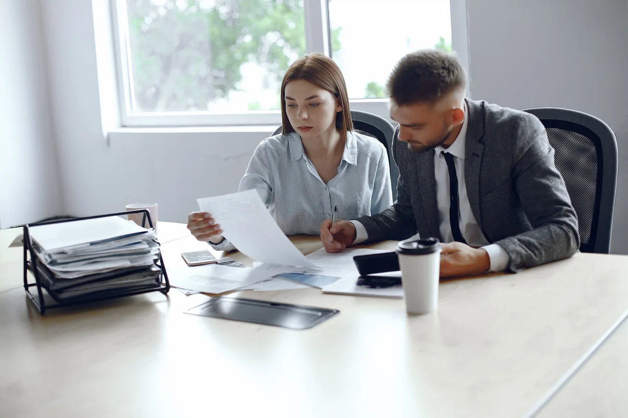 A tax adviser and a colleague working through paperwork at a desk