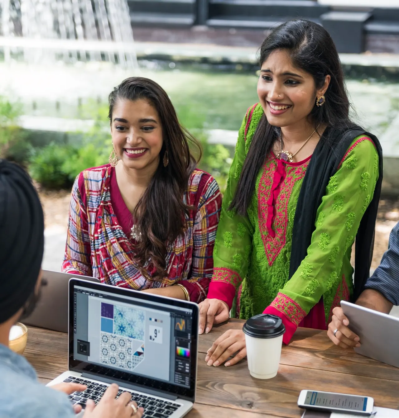 Colleagues gathered around a laptop showing a pattern design in a graphics editor