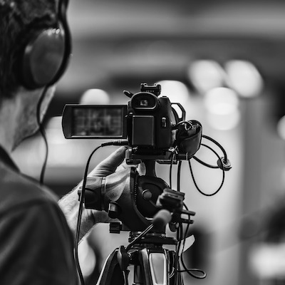 A camera operator in headphones filming an event with a professional video camera