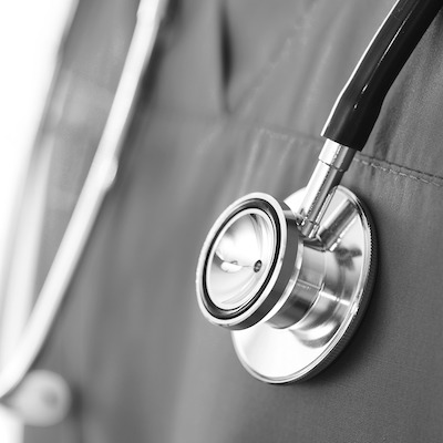 A close-up of a stethoscope worn over a clinician's scrubs