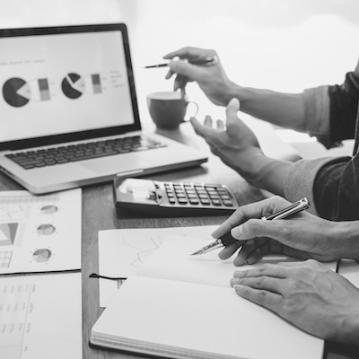 Hands reviewing printed charts beside a laptop and a calculator