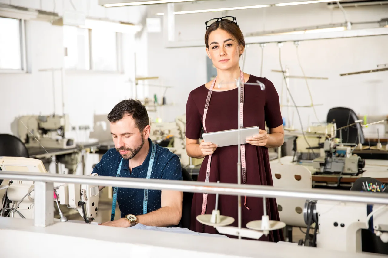 A production manager with a tablet on a clothing factory floor