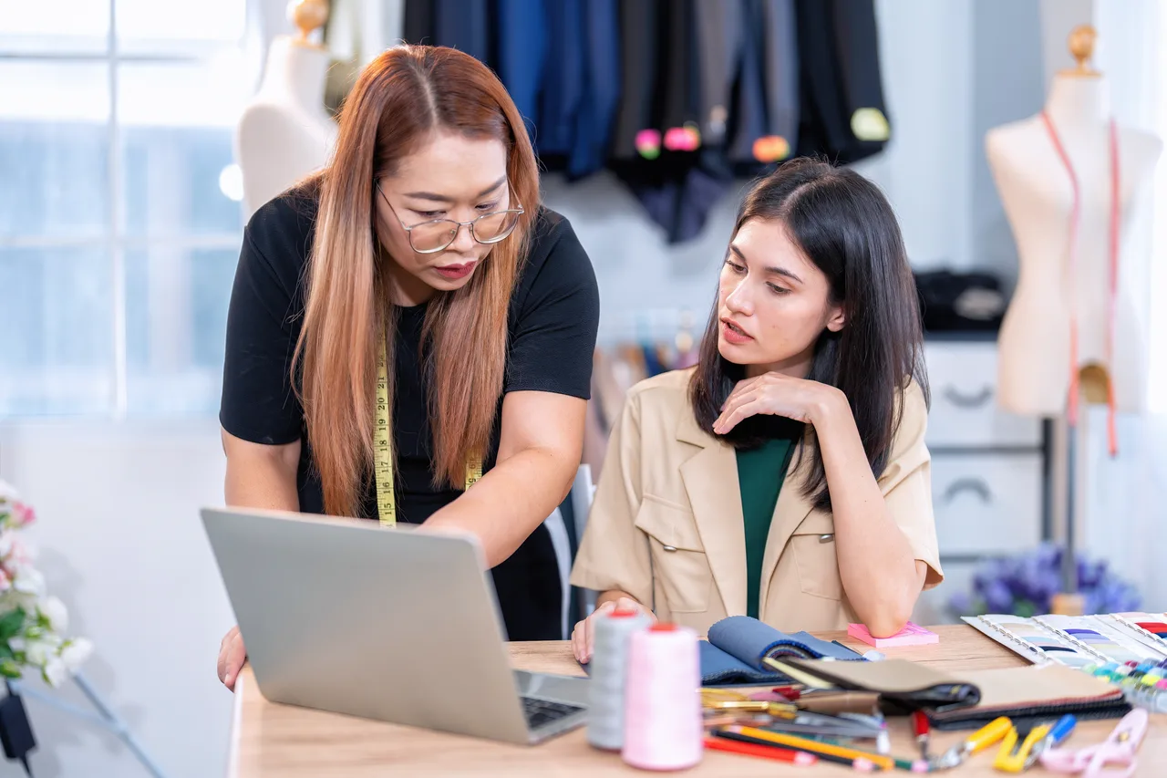 Two designers working together at a laptop in a fashion studio