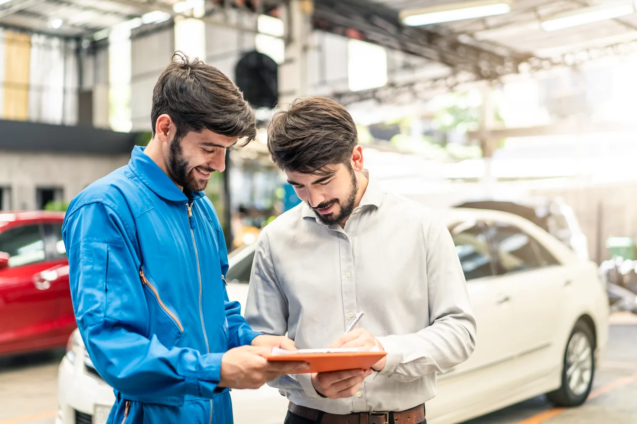 A service technician talking a customer through repair details in a garage