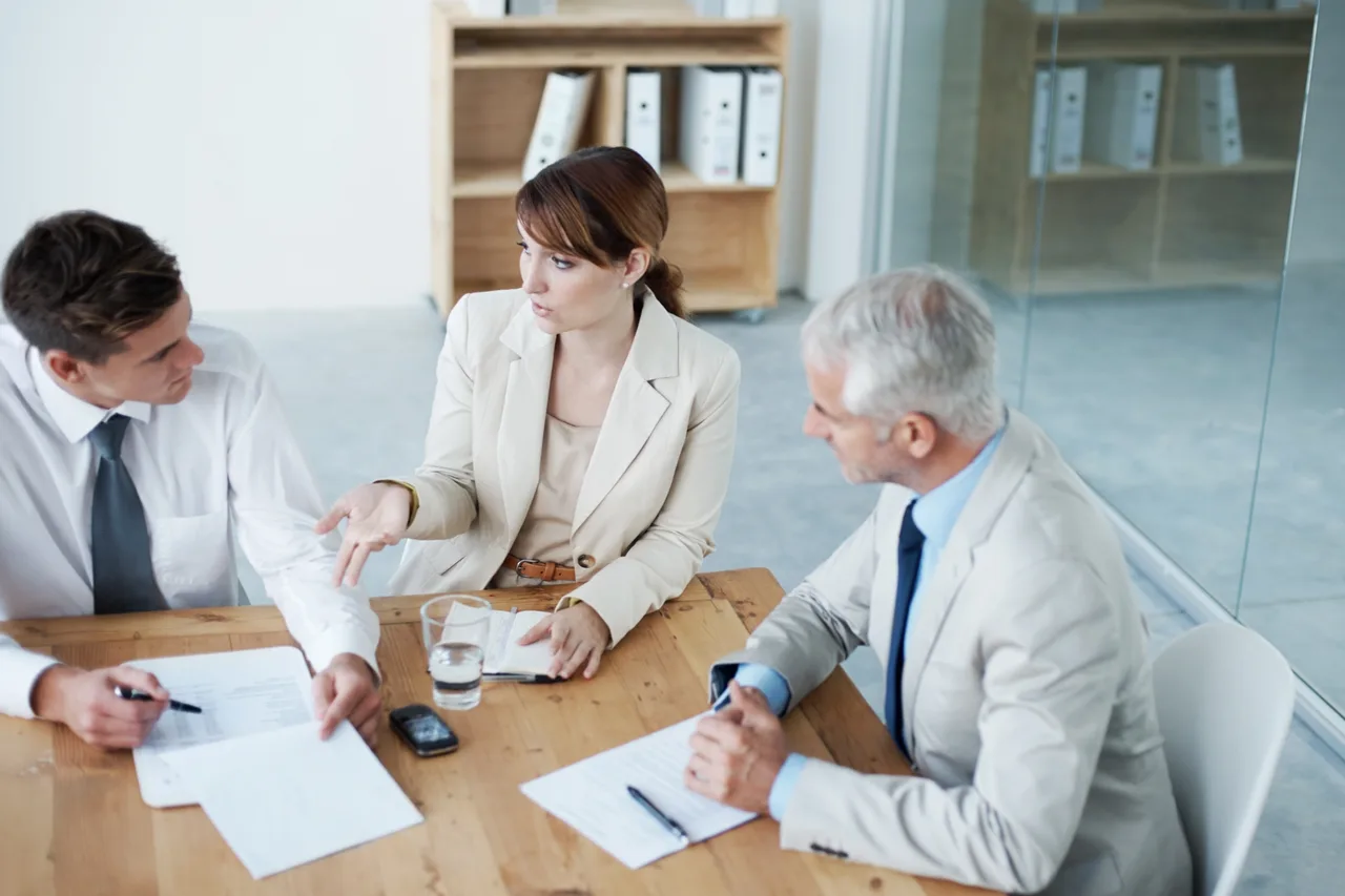 Three colleagues working through documents together at a table