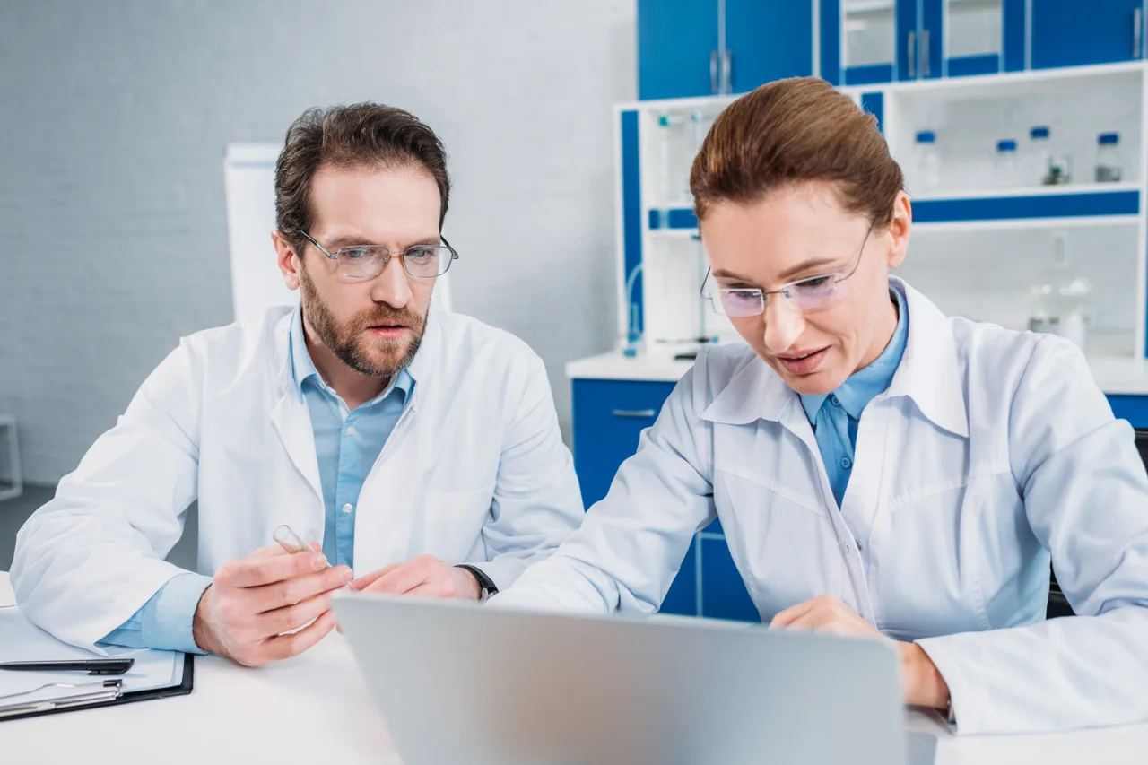Two scientists reviewing data on a laptop in a lab