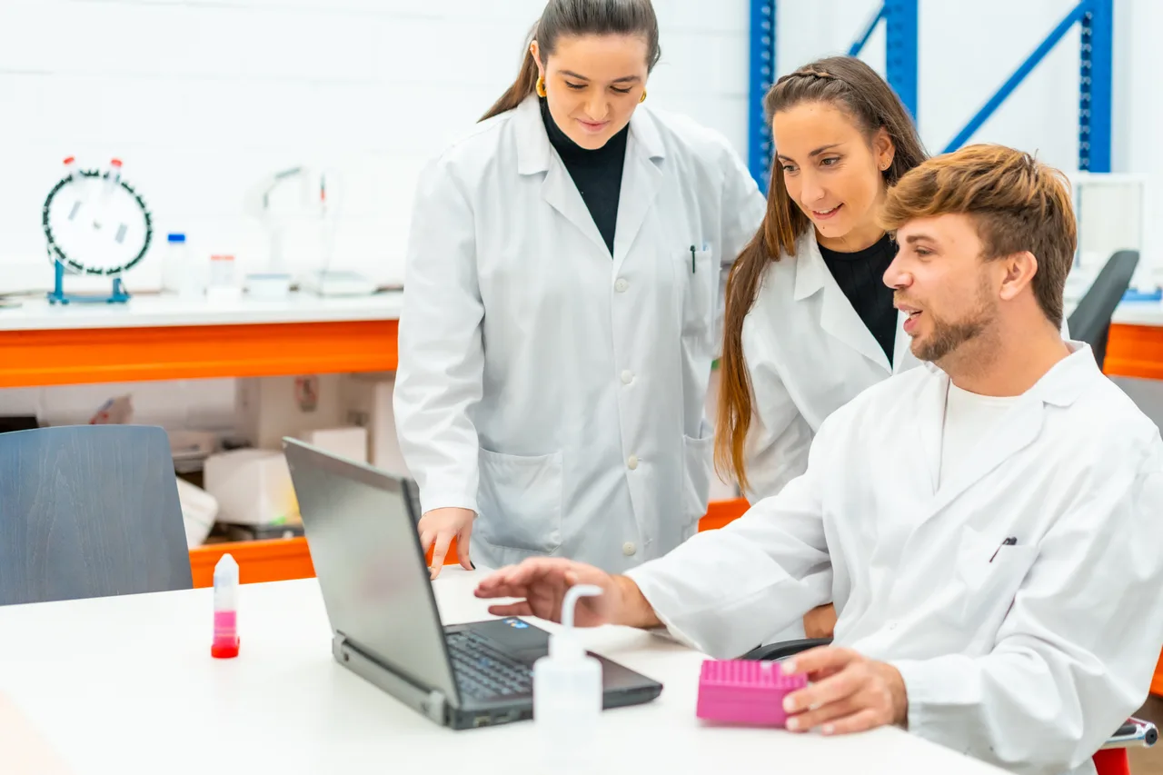 Three researchers planning together around a laptop in a laboratory