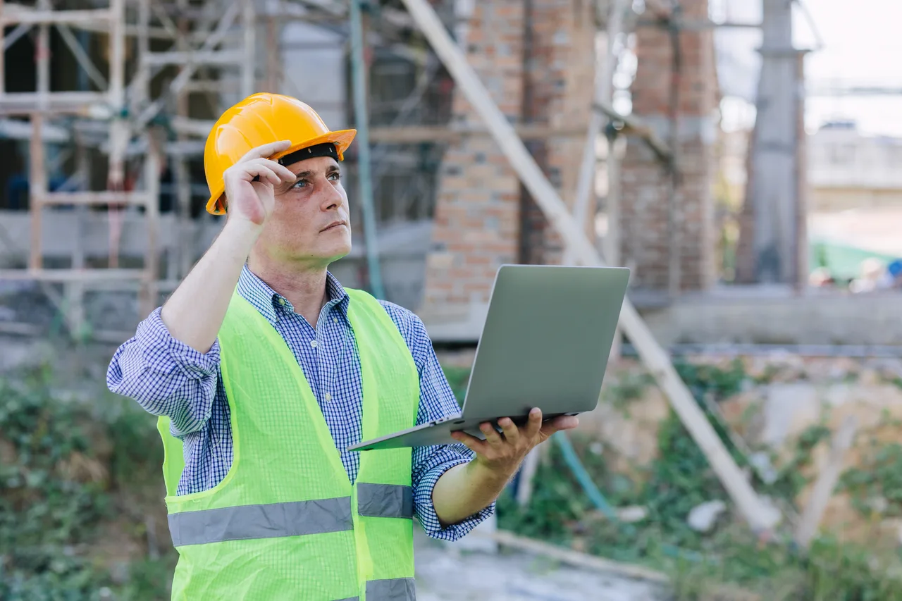 A construction supervisor working on a laptop at a building site
