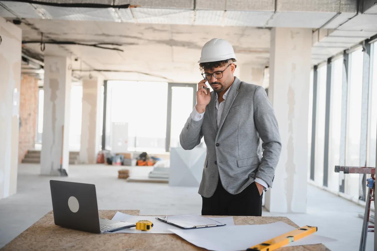 A project manager on a phone call inside a building under construction