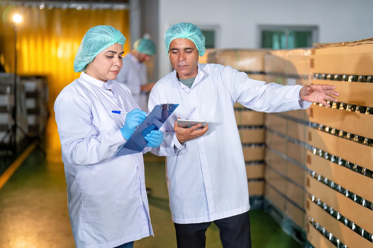 Two quality inspectors checking products and taking notes