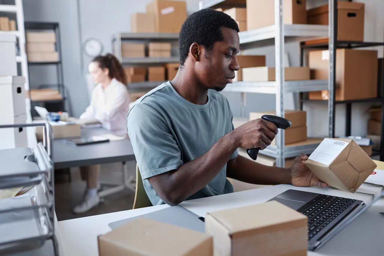 A fulfilment worker scanning a parcel beside a laptop