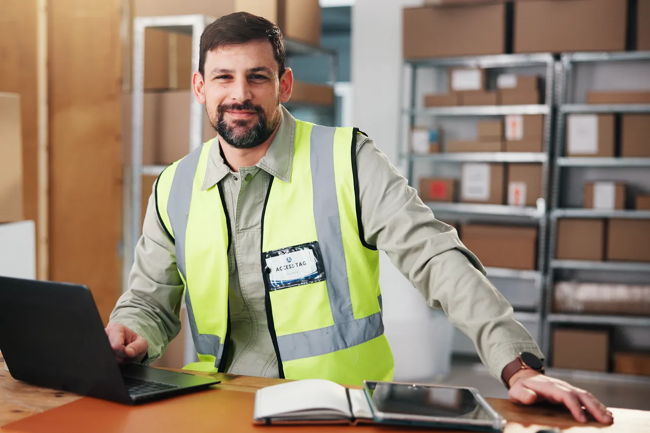 A warehouse manager working on a laptop in a logistics centre