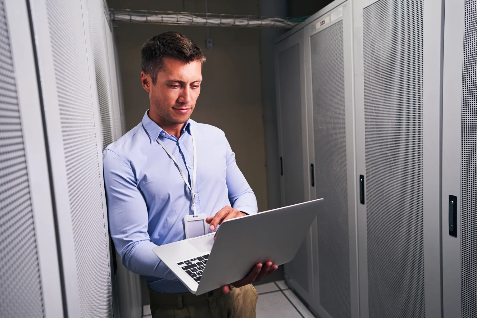 An administrator working on a laptop in a server room