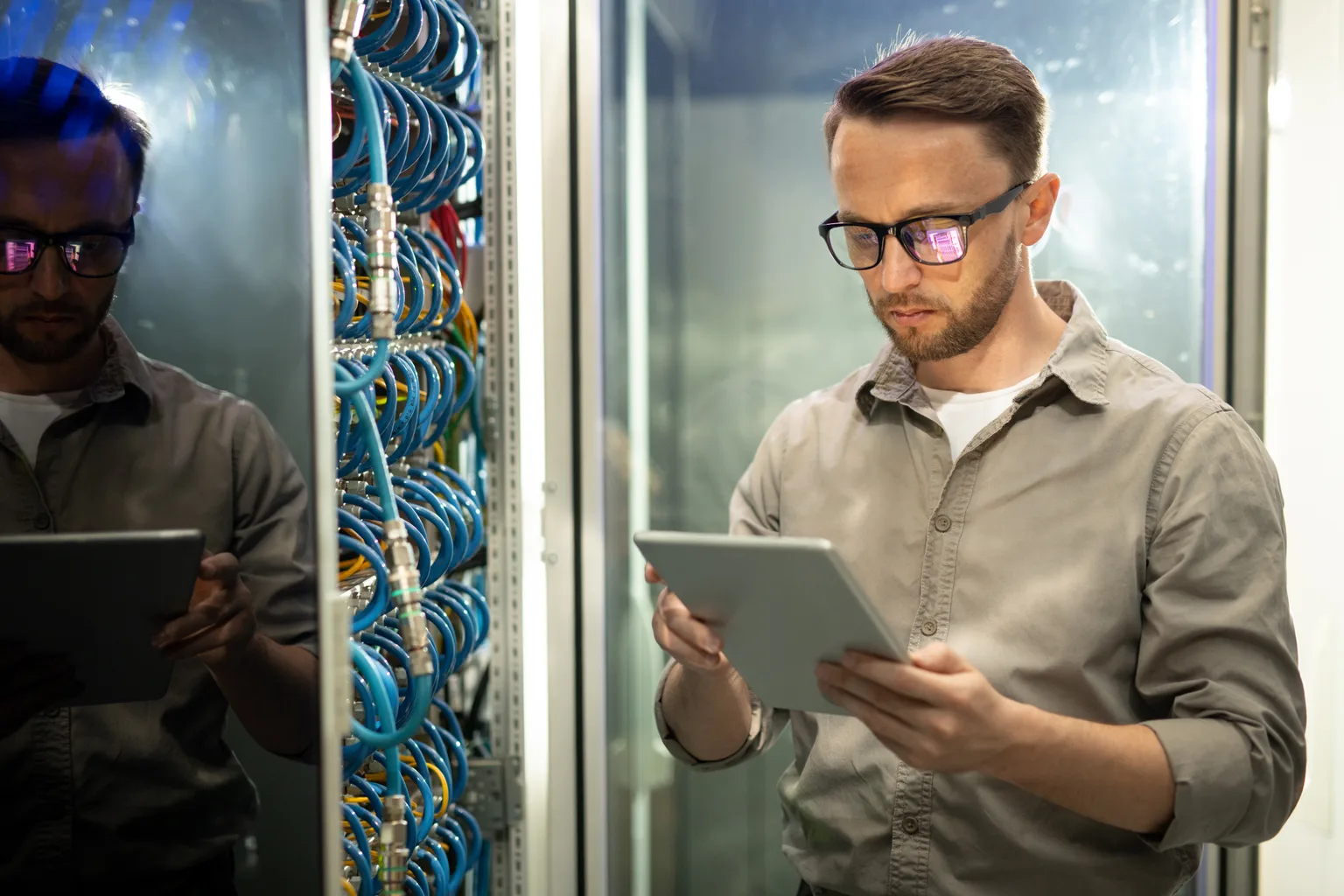 An engineer checking a cabled server rack against a tablet