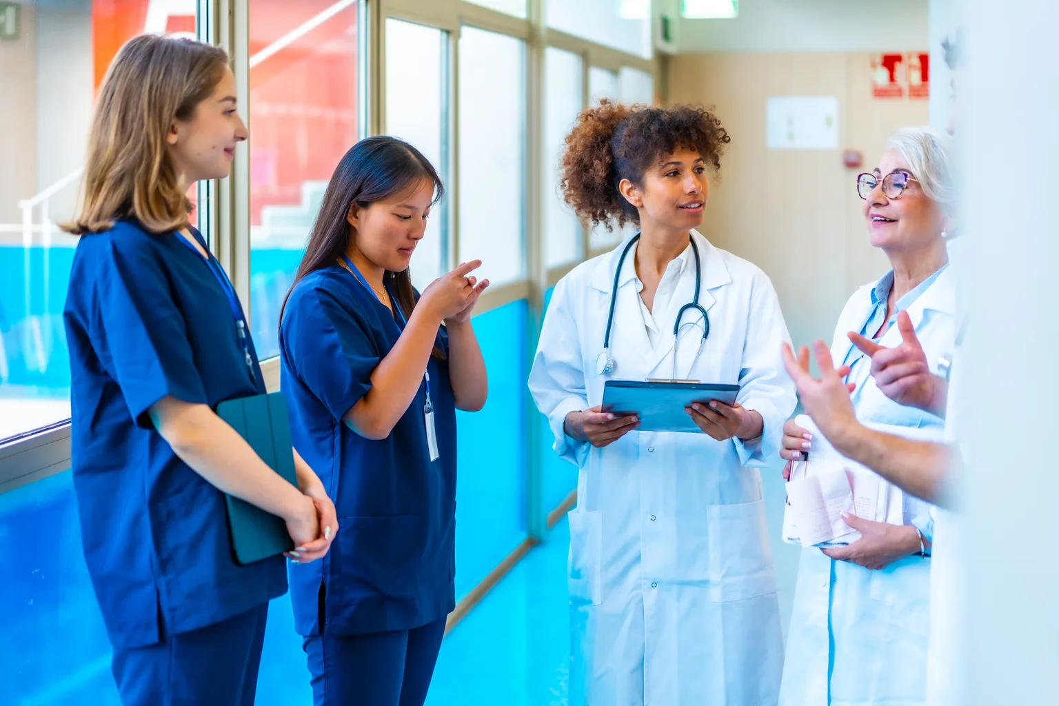 Nurses and doctors talking through roles in a hospital corridor