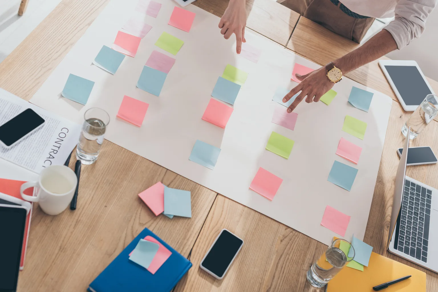 Hands arranging planning notes in sequence on a table