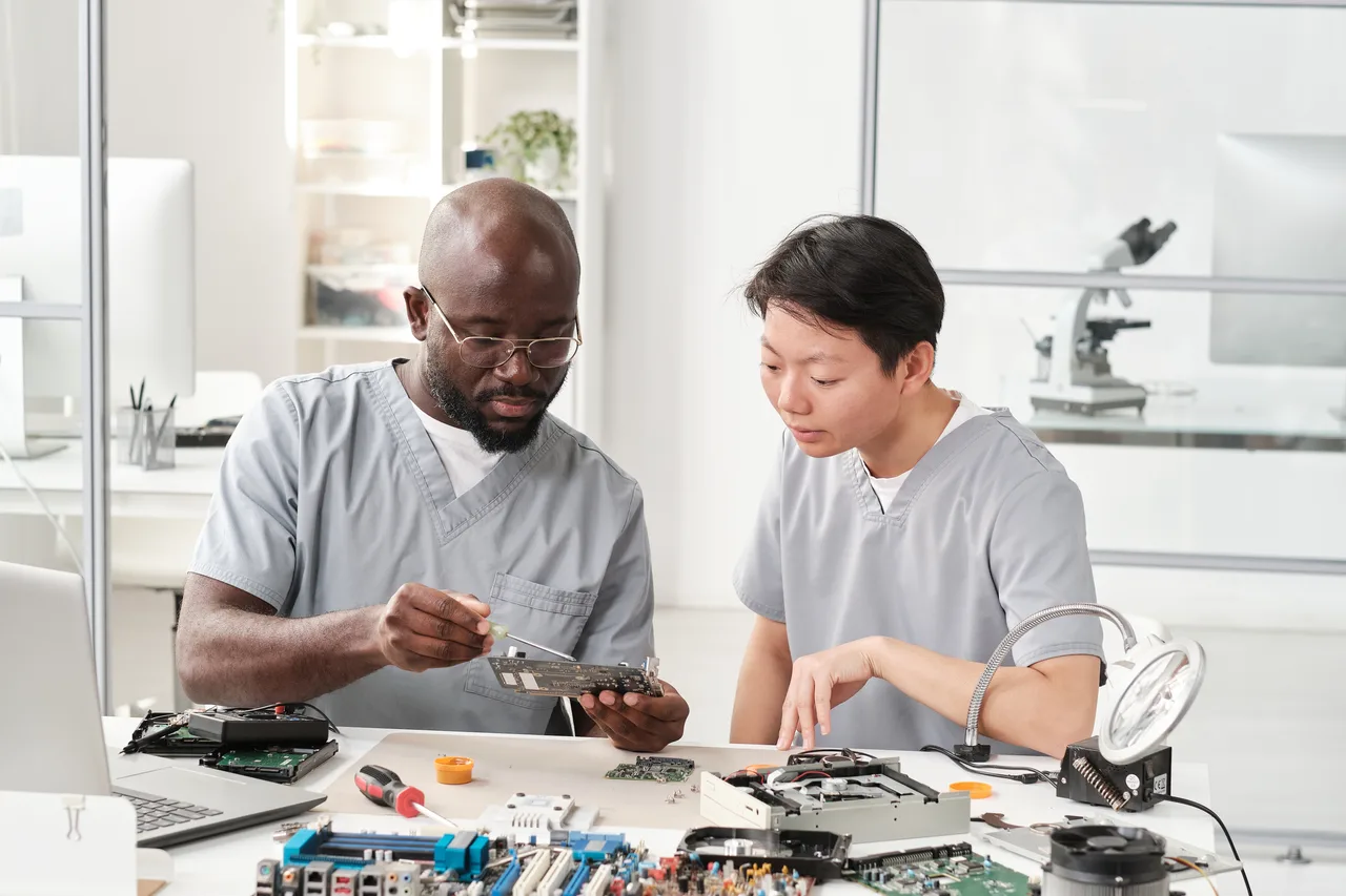 Two technicians working on circuit boards at a repair desk