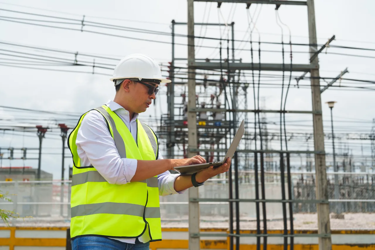 An engineer working on a laptop at a power substation