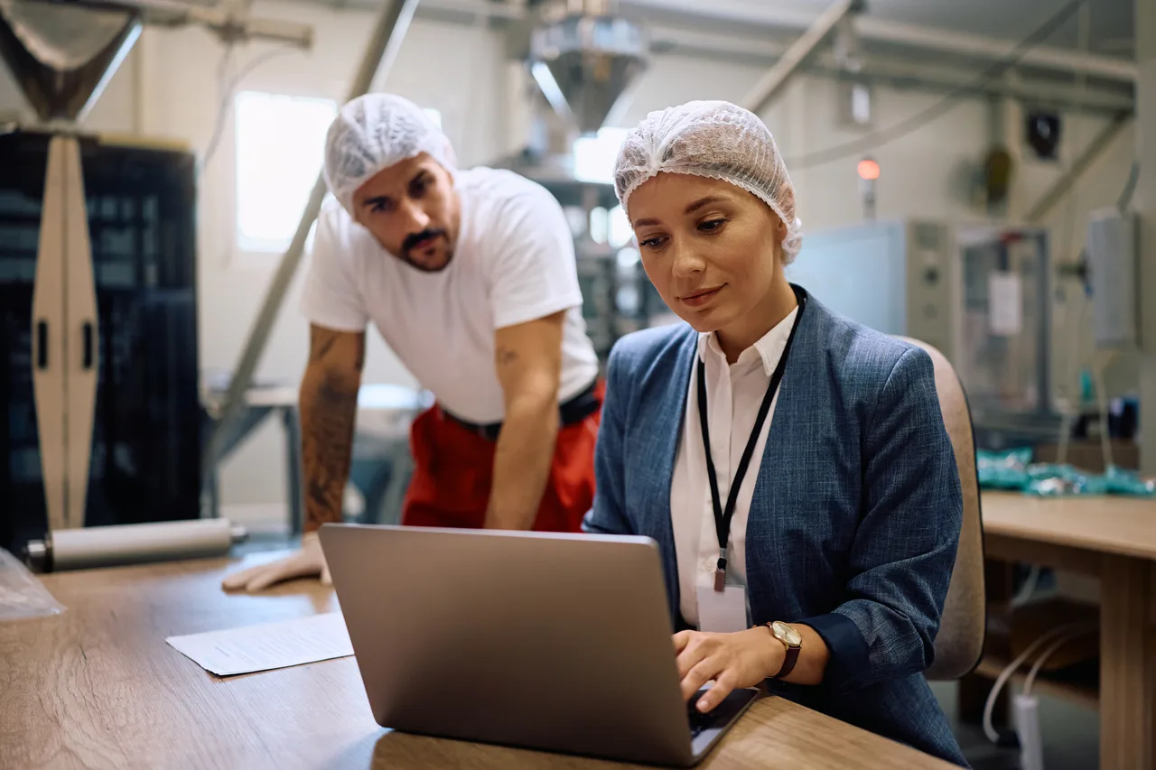 A plant manager and a production worker working through a procedure on a laptop