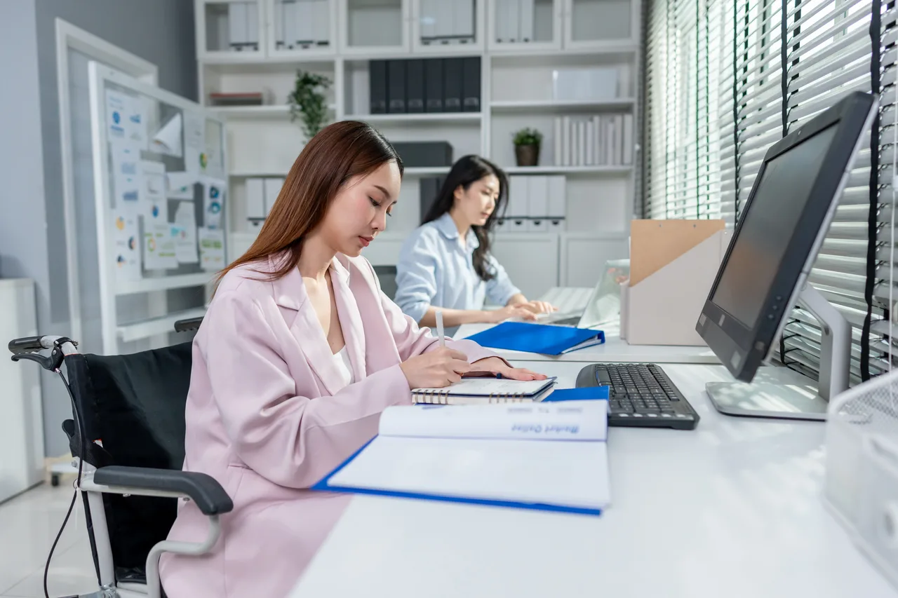 Two claims staff working at computers in a bright office