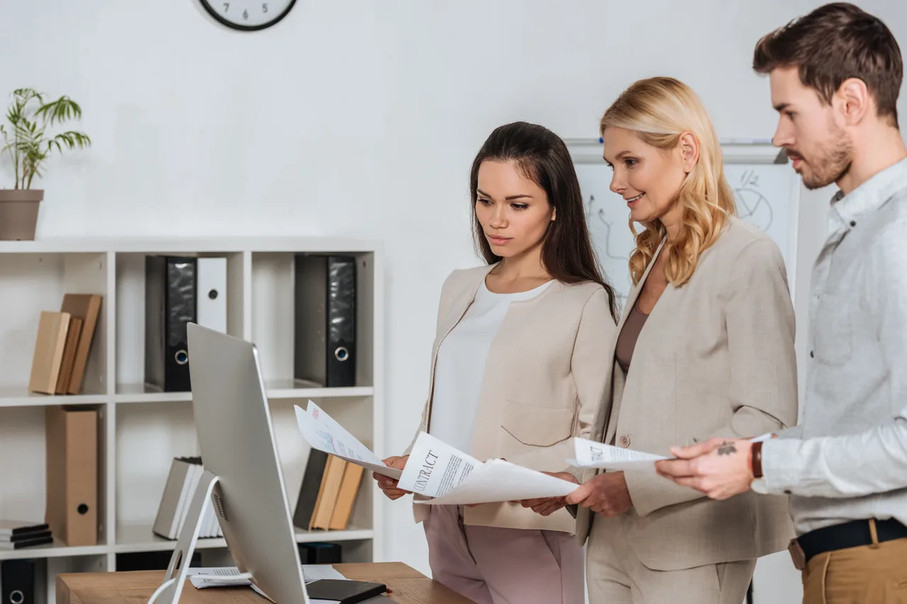 Three colleagues reviewing a policy contract in an office