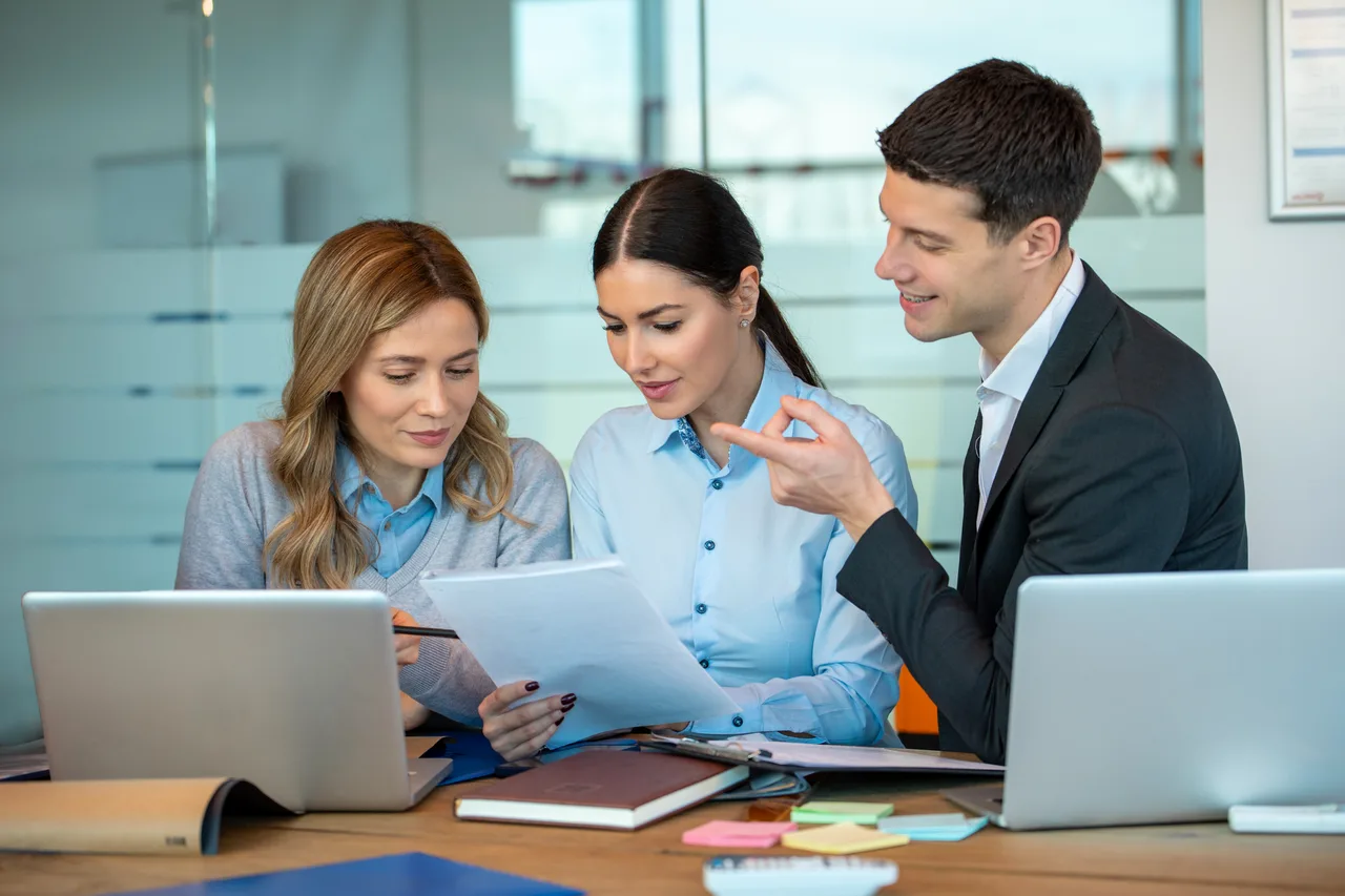 Three professionals reviewing documents together at a desk