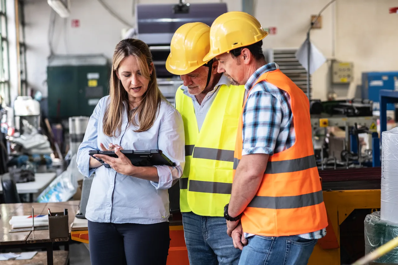 Three colleagues reviewing a tablet on the factory floor