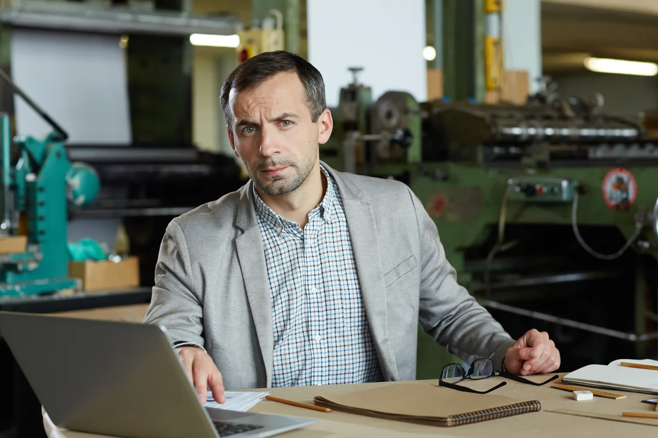 A production manager working at a desk in an industrial office