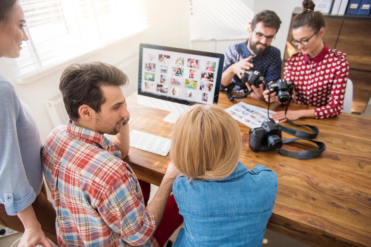 A production team reviewing shots around a desk with cameras and a computer