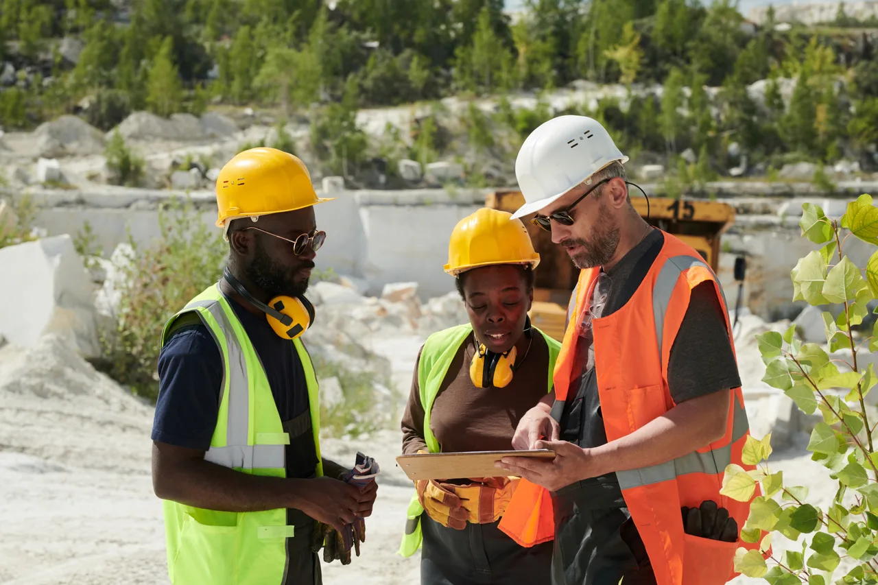 A team in safety gear reviewing plans at a quarry