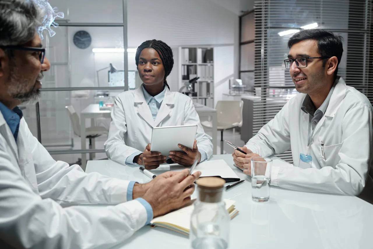 Three scientists discussing work around a table