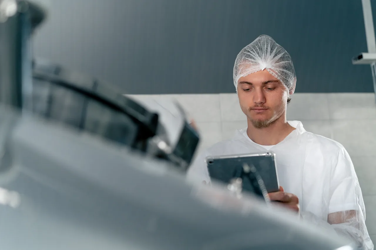 A cleanroom operator checking production equipment on a tablet