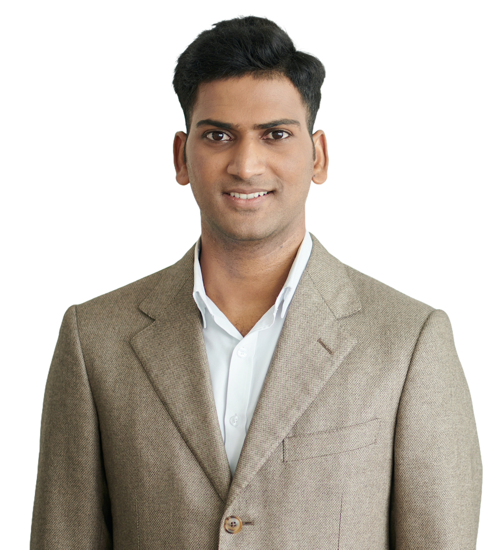 A smiling engineer in a beige blazer over an open-collared white shirt