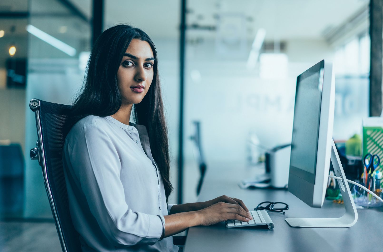 A woman working at a desktop computer in an office