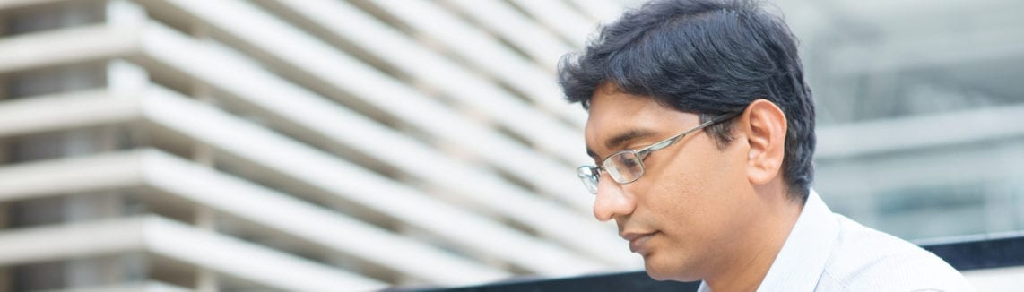 Candid Asian Indian businessman using laptop computer, modern bu
