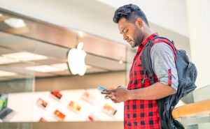 RIMINI ITALY - JUNE 24 2016: Man using smartphone in front of Apple store located in a shopping center on Via Caduti di Nassiriya Rimini ITALY