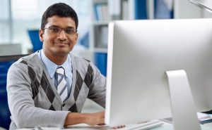 Smiling young software developer working on computer
