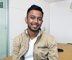Young Indian man smiling at camera in his office